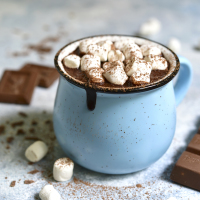 Homemade hot chocolate with mini marshmallow in a blue enamel mug on a light slate background.