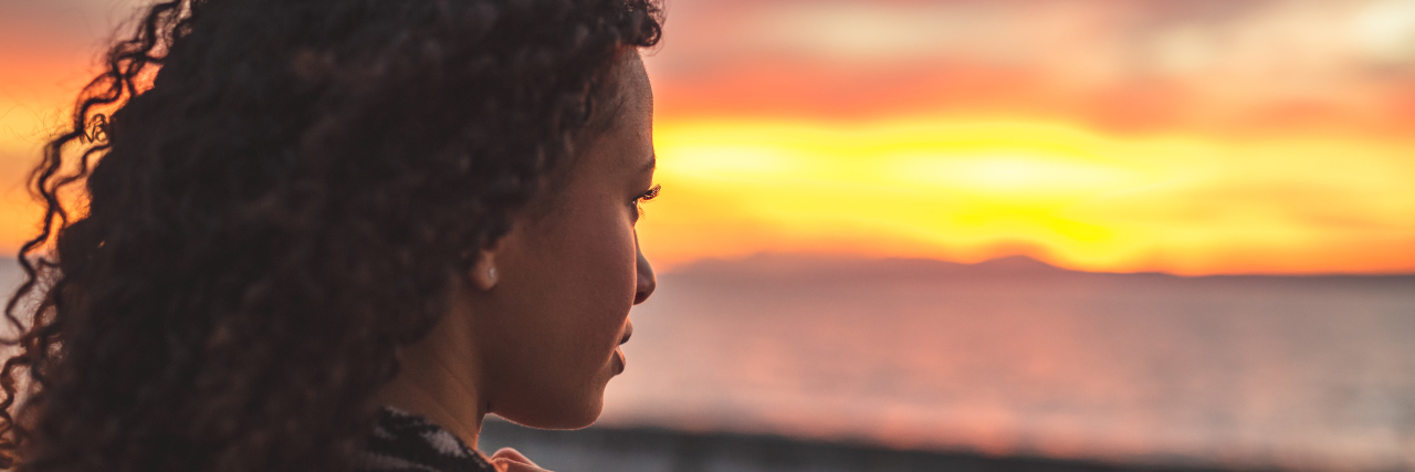 15 Common Misconceptions About Chronic Illness Young African American woman is standing on the beach.