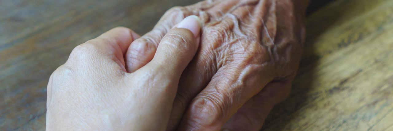 Young woman holding elderly woman's hand.