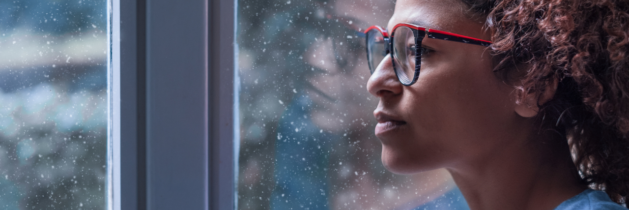 How to Survive the Holidays When You Live Alone woman looking out a window