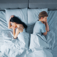 couple in bed laying away from one another