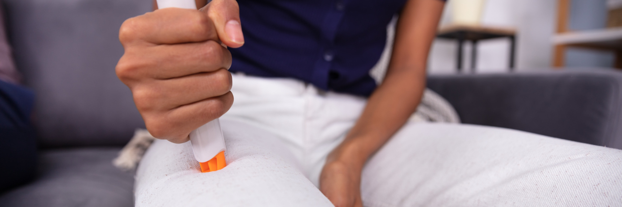 woman injecting her thigh with an EpiPen