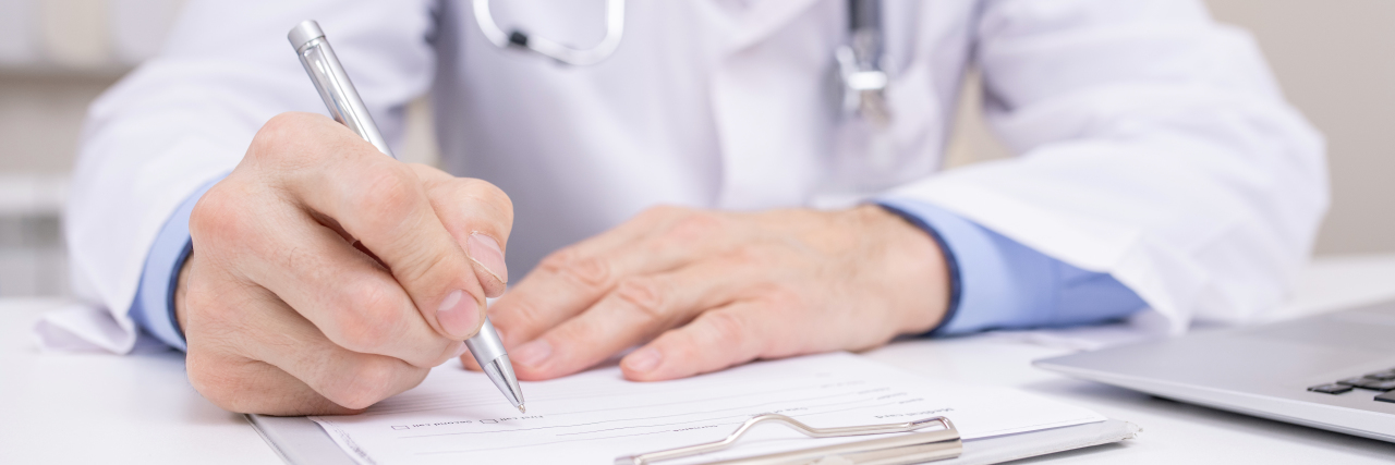 When a Rheumatologist Said I'm 'Not Sick Enough' for Treatment Doctor writing in patient chart.