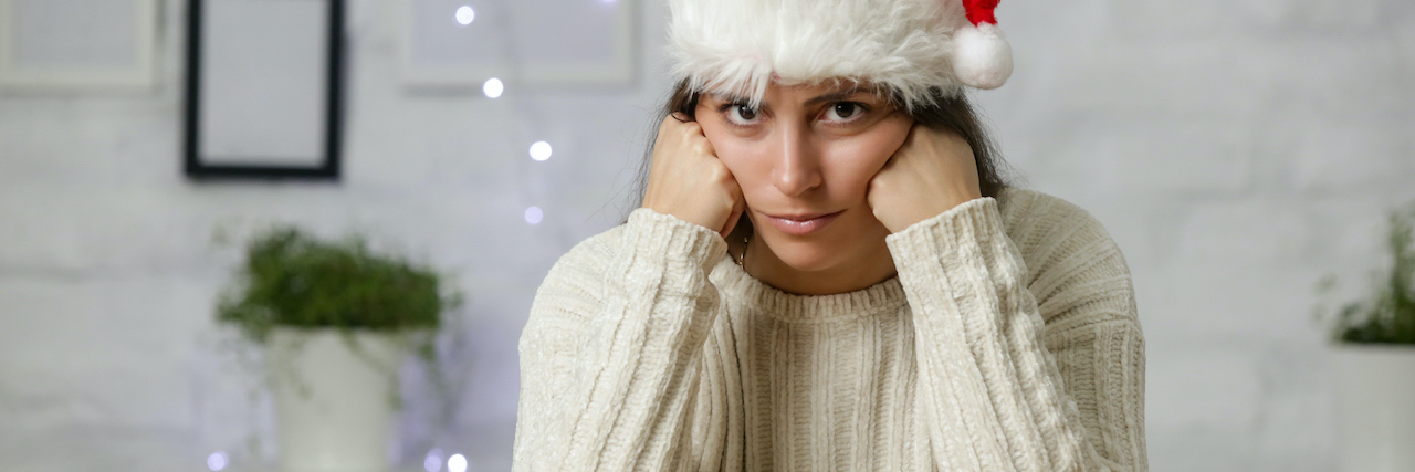 A woman wearing a Santa hat looking grumpy