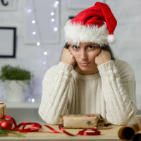 A woman wearing a Santa hat looking grumpy