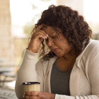 Middle age woman in deep thought sitting at a table with a mug