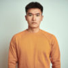 Young man wearing an orange sweater looking forward