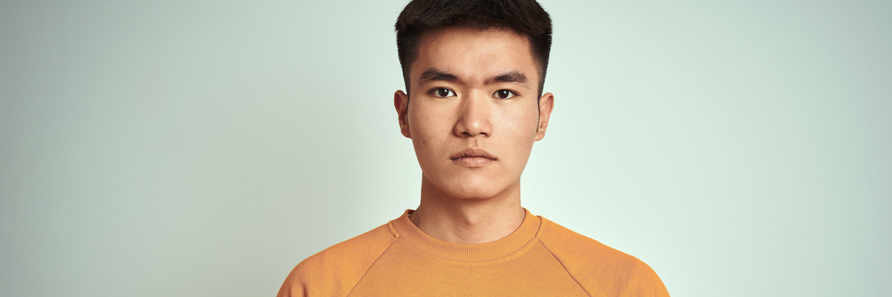 Young man wearing an orange sweater looking forward