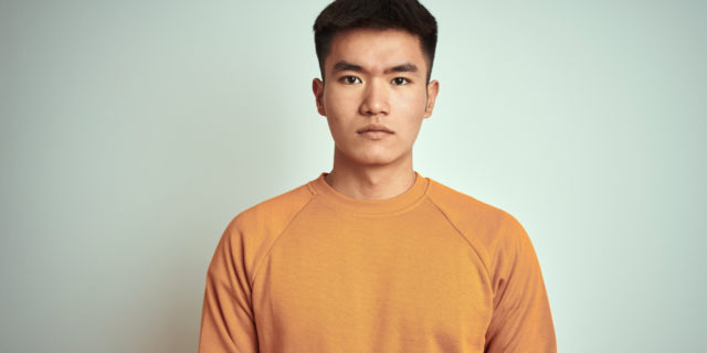 The Disease I Might Have Terrifies Me Young man wearing an orange sweater looking forward