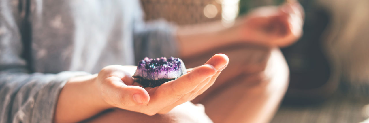 Why the Law of Attraction Is Ableist person meditating with a crystal