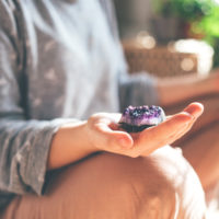 person meditating with a crystal