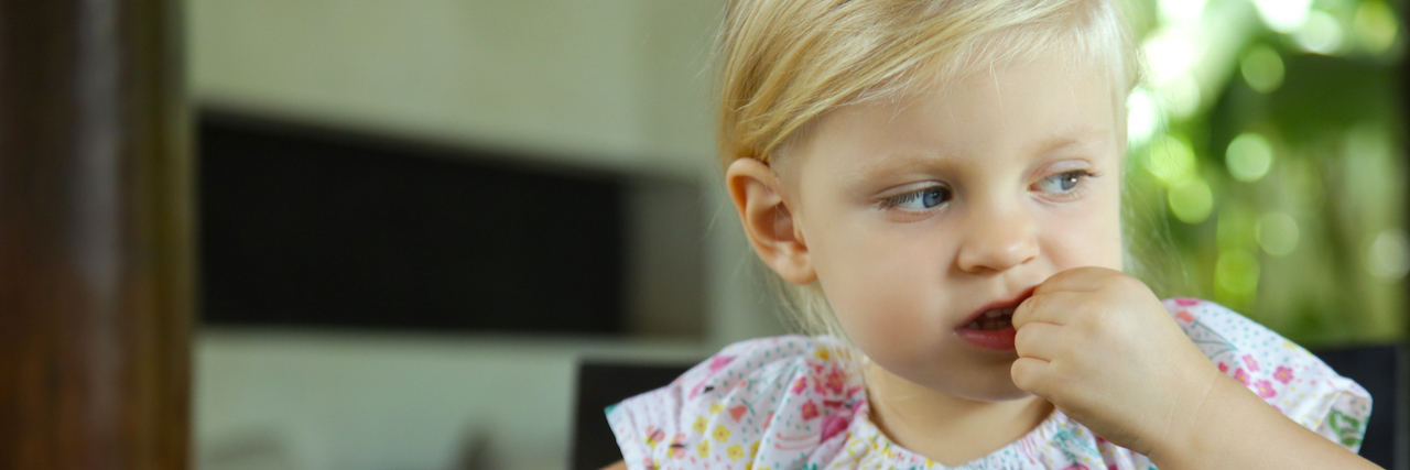 Why We Need to Stop Referring to IgE-Mediated Allergies as 'True' Food A young girl eating nuts, sitting at a table