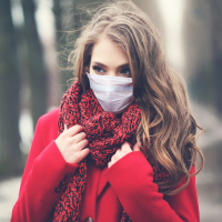 Woman wearing face mask and winter coat.
