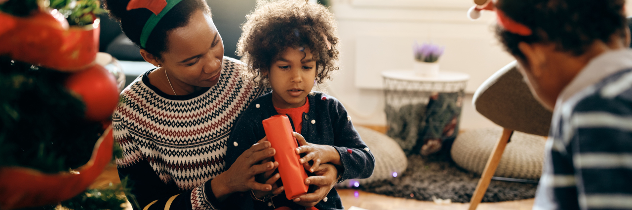 5 Holiday Tips for Parents of Kids With Autism and Other Disabilities Happy African American mother with kids opening Christmas presents at home.