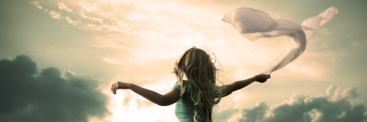 Changing How I Define Hope in Life With Chronic Illness Woman in turquoise dress dancing with scarf at sunset.