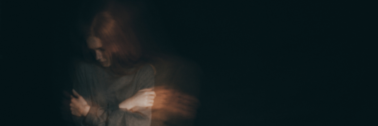 My Battle With Addiction as an Adult With Cerebral Palsy Sad woman wrapping her arms around her chest.