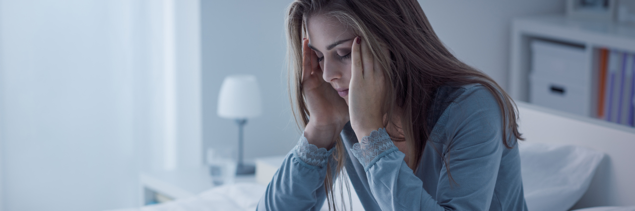 Recovery and Moving Forward After Losing Time Due to Depression photo of woman sitting upright in bed with eyes closed and hands either side of head