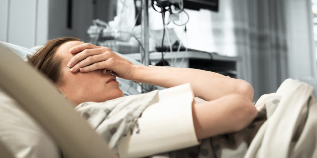 The 6 Words That Saved My Life in the ICU a woman in a hospital bed, with her hands covering her face