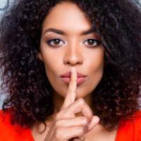 Shh! Closeup portrait of woman with finger in front of her lips.