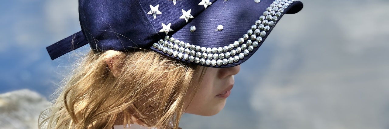 a young girl wearing an american flag cap looking into the distance