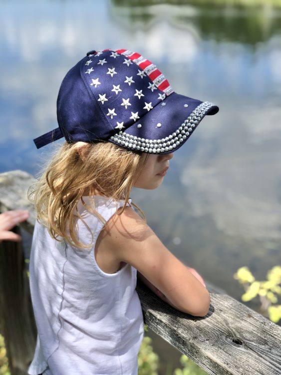 a young girl wearing an american flag cap looking into the distance