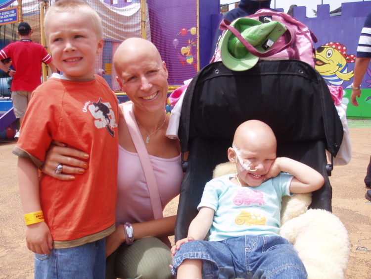 a mom with cancer hugging her young son and young daughter with cancer
