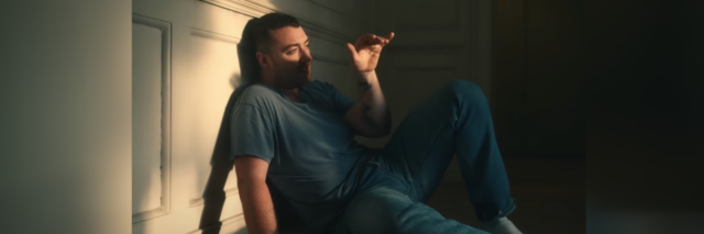Sam Smith sitting against a wall with light on him