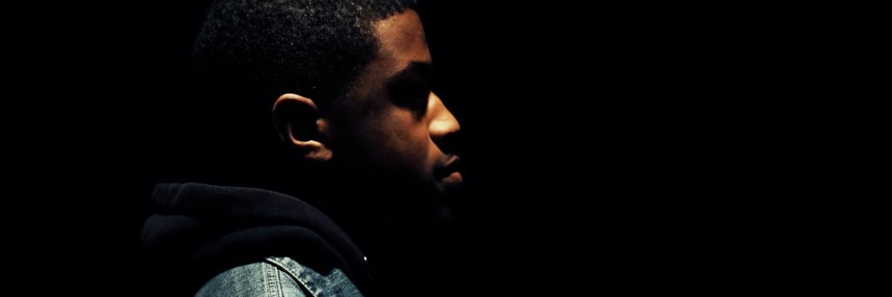 Self-Care Reminders for Coping With Emotions Over the Holidays photo of man in profile standing in darkness