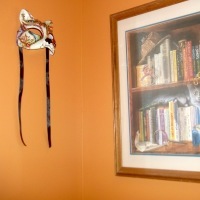 photo taken by the contributor showing a framed picture of a bookshelf and a cat mask on her reddish sensory room walls
