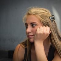 photo of young woman resting head on hand lost in thought