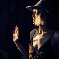 photo of woman holding up her hand in darkness, illuminated by light through window