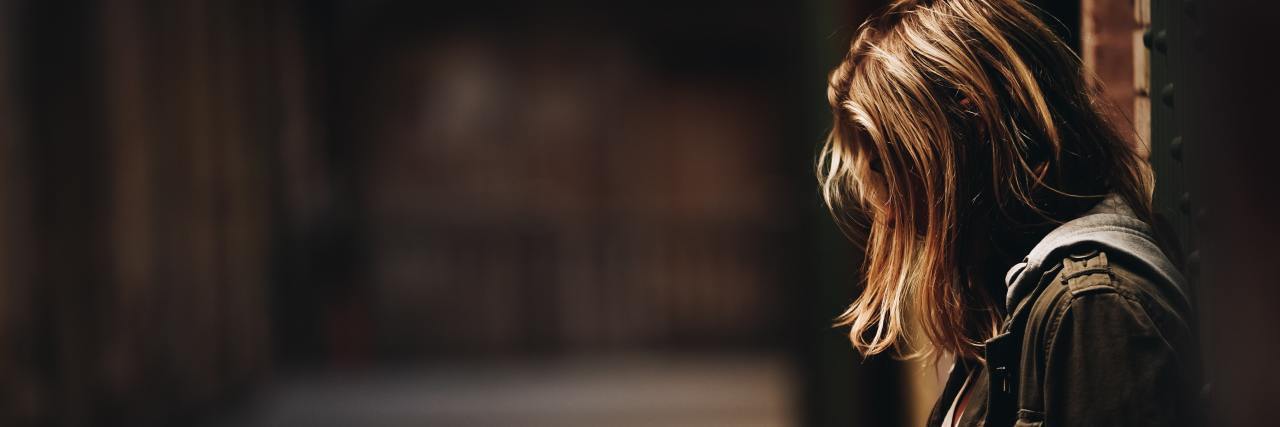 What to Know About 'Nothing Days' When You Live With Asthma  Profile of a woman looking down, face hidden, in an empty alley