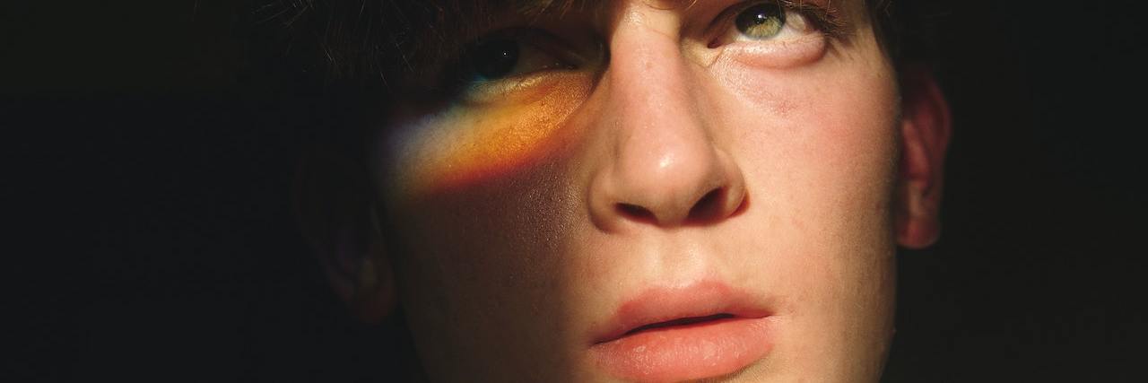 Neuro-queer and Gender-vague: Why I Don't Capitalize My Name A man with a beam of rainbow on his face