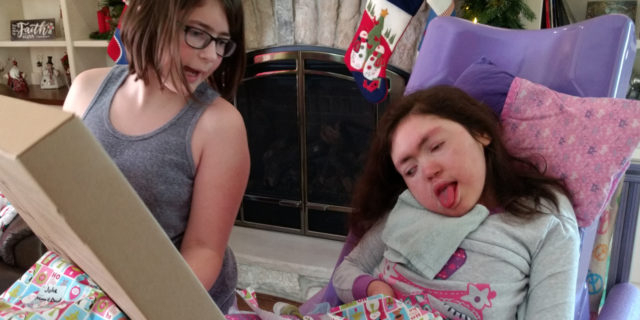 Finding the Right Gift for Teens With Developmental Delays Teen Julia enjoys opening holiday gifts with her sister Erica.