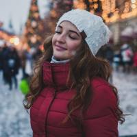 photo of woman in winter with christmas tree behind her, smiling with her eyes closed