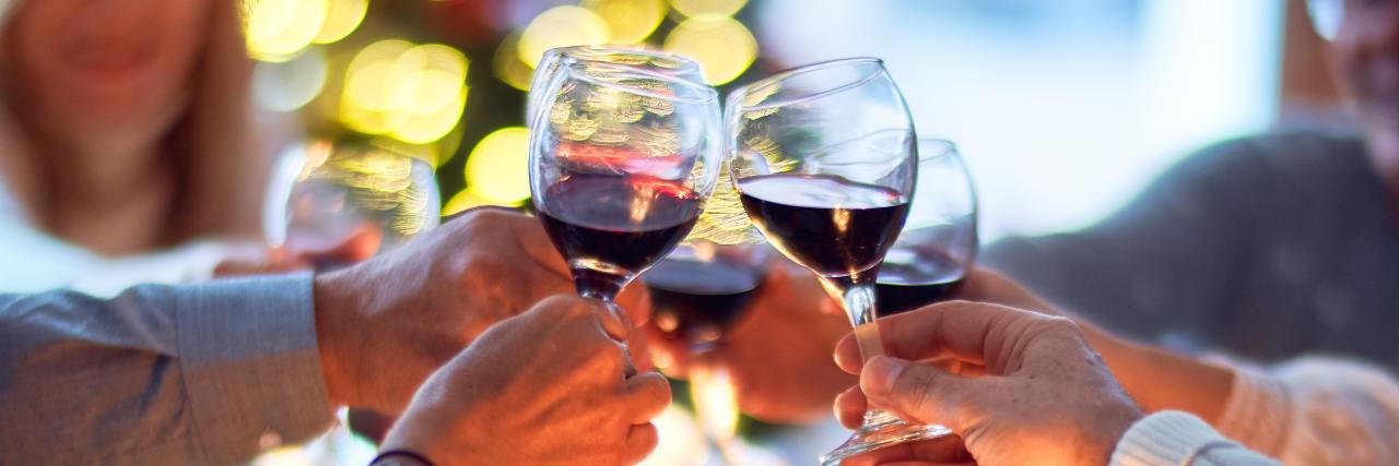 How To Reject Diet Culture This Thanksgiving and Holiday Season photo of thanksgiving or christmas dinner with people raising glasses in a toast over dinner table