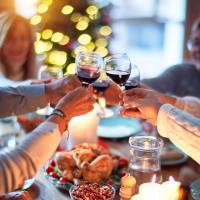 photo of thanksgiving or christmas dinner with people raising glasses in a toast over dinner table