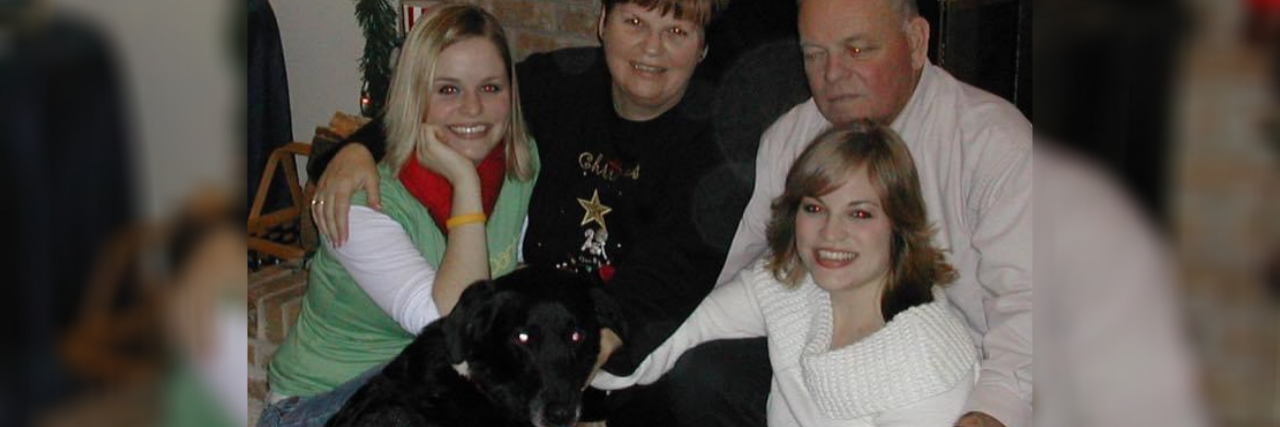 Lauren with her parents and sister in front of the fireplace at Christmas.