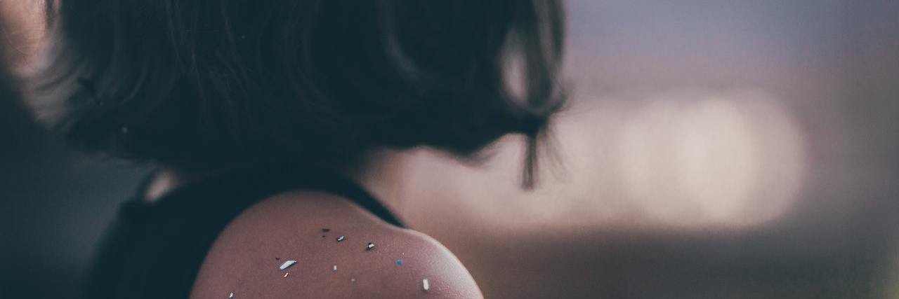 Back a woman's head as she looks off toward blurry lights in the distance