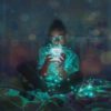 photo of woman sitting on bed with blue LED string lights in a jar and around her, holding it close to her face