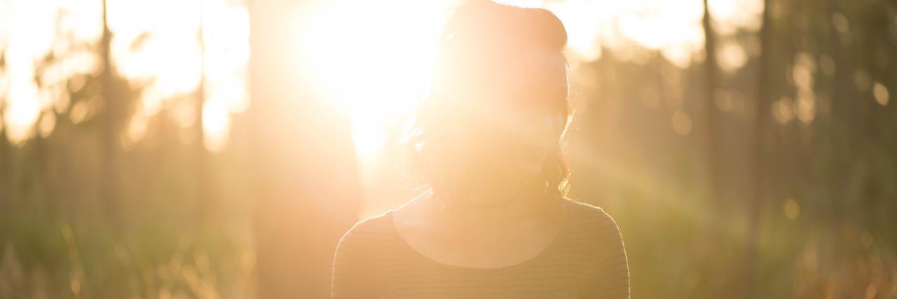 There Is More Than One Way to Manage Intrusive Thoughts woman with the sun shining on her face walking in a forest