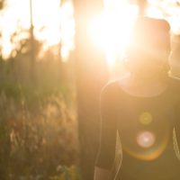 woman with the sun shining on her face walking in a forest