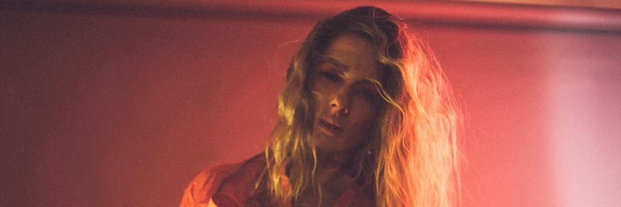 Can Derealization Be a Symptom of PTSD? A woman with long blonde hair wearing a pink suit out of focus and blurred