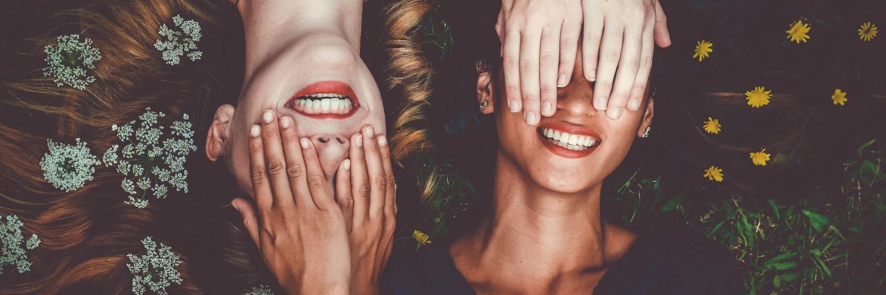 When I Discovered Even a Confident Friend Has Anxiety Too photo of two women lying on ground, covering each others eyes, with flowers in their hair