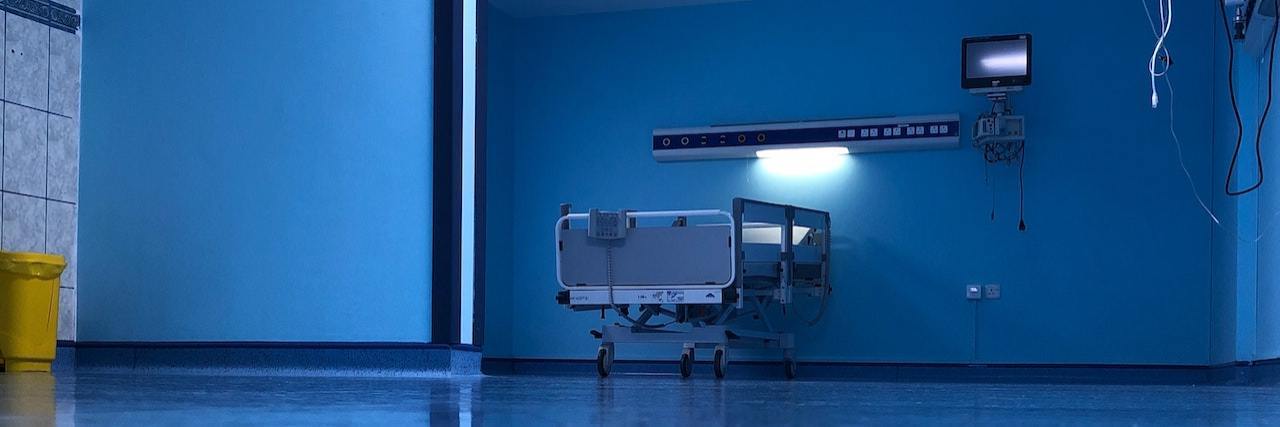 Empty hospital ward with low lighting and an empty hospital bed against the wall