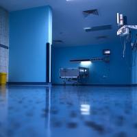 Empty hospital ward with low lighting and an empty hospital bed against the wall