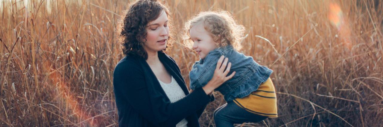 photo of woman holding young smiling girl or daughter in a field