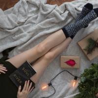 overhead photo of woman with christmas lights and a book in her lap