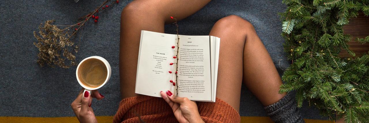 overhead photo of woman reading a book and drinking coffee