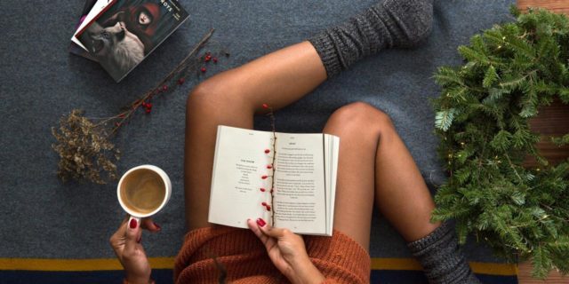 overhead photo of woman reading a book and drinking coffee